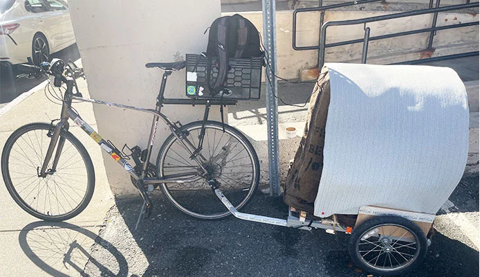 The bike with the cooling trailer attached, jute sack over the load and a light canopy on top
