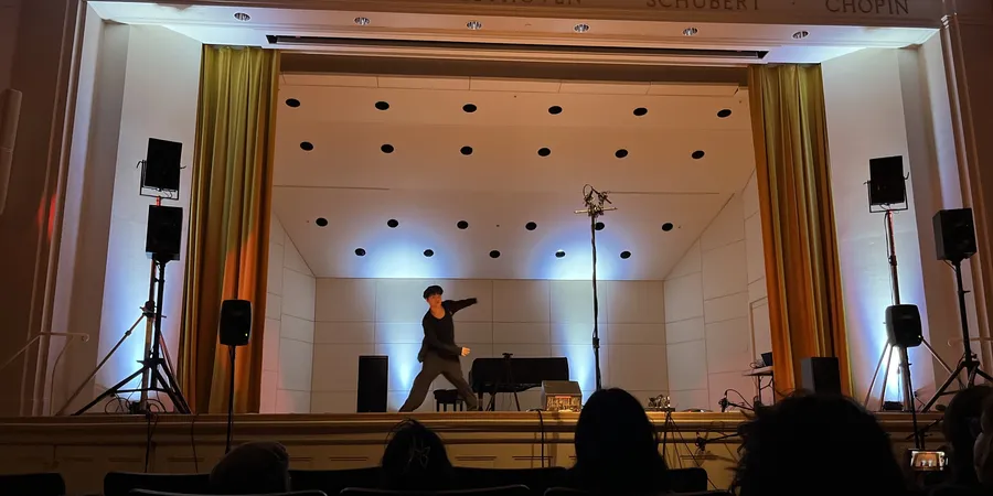 Zhixing Chen dancing the opening solo on the Paine Hall stage, audience in the foreground